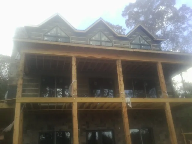 Dormers and porch framing on a large log home under construction — Roof Coating work by our crew in Cordova