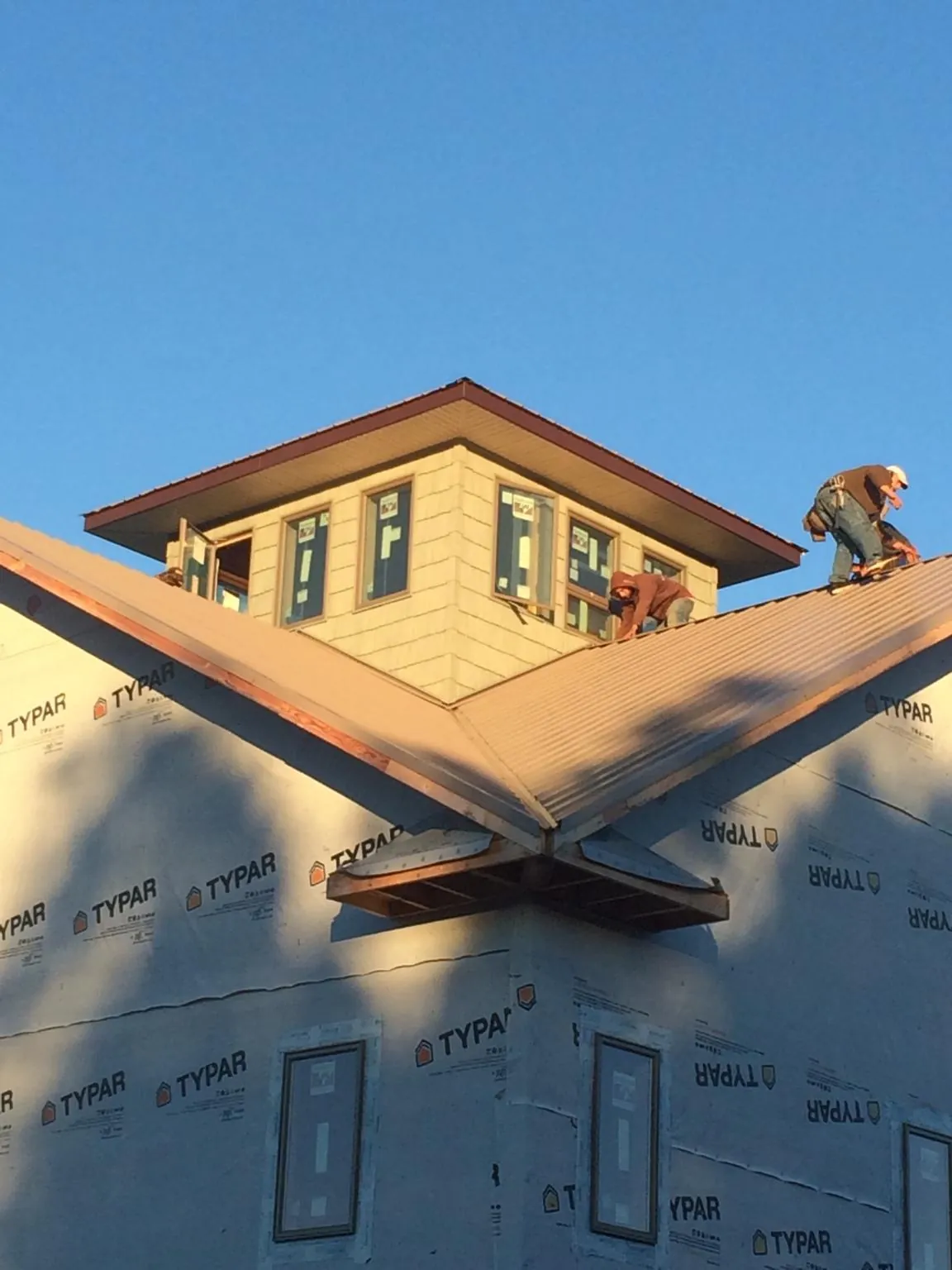 Roofers working around a rooftop cupola on a new metal roof at sunset — Roof Waterproofing in Cordova by Roofing Brothers